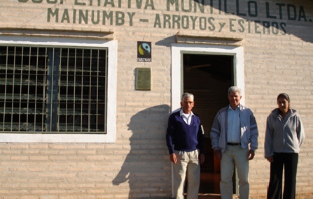 Mitglieder der kooperative Manduvira in Paraguay vor einem ihrer Gebäude mit Fairtrade-Schild