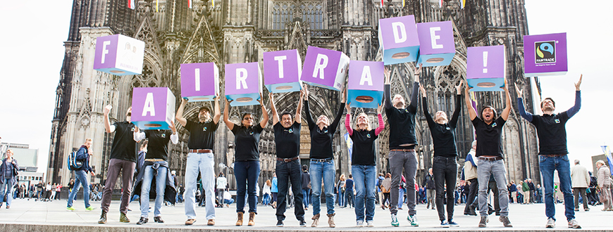 TransFair-Team wirft Fairtrade-Würfeln vor dem Kölner Dom in die Luft