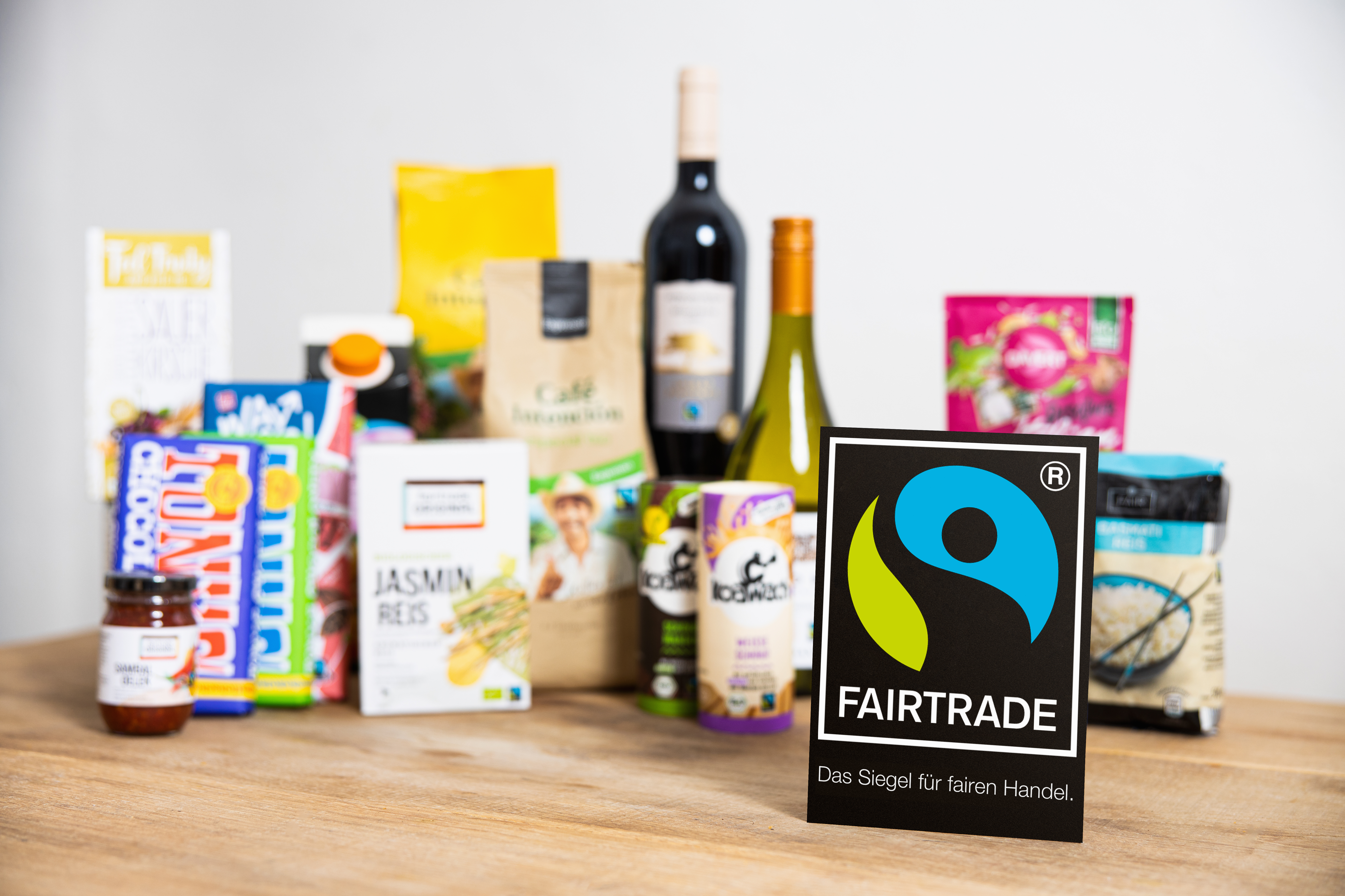Fairtrade-Produkte stehen auf einem Tisch, das Produktsiegel steht davor.