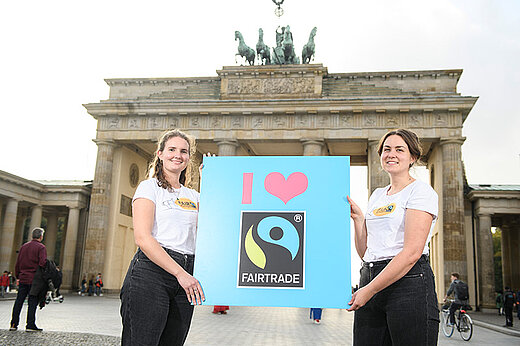 Zwei FairActivists mit Aktions-Schild vorm Brandenburger Tor in Berlin