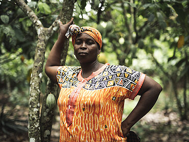 Eine Kakaoproduzentin steht im Kakaofeld. 