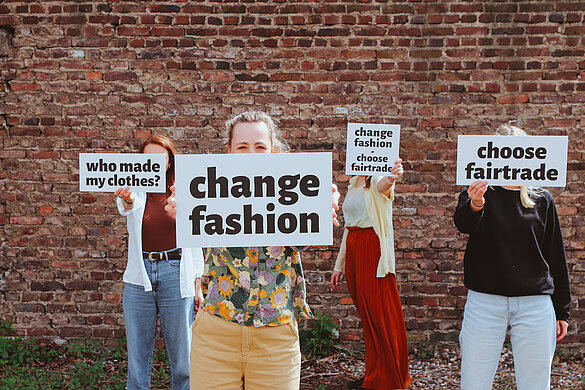 Junge Erwachsene mit Protestschildern "Change Fashion"