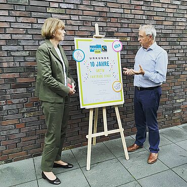 Dieter Overath, Vorstandsvorsitzender von Fairtrade Deutschland, überreicht Kölns Oberbürgermeisterin Henriette Reker die Urkunde zum Jubiläum 10 Jahre Fairtrade-Town Köln