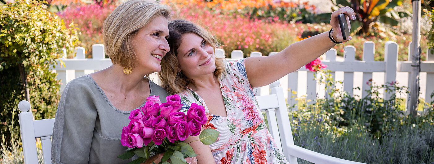 Zwei Frauen machen ein Selfie mit einem Blumenstrauß. Bild: Fairtrade Österreich