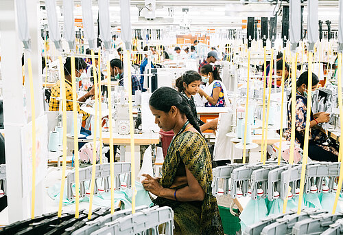 Textilarbeiterinnen und Textilarbeiter bei der Arbeit in einer Fabrik in Indien.  