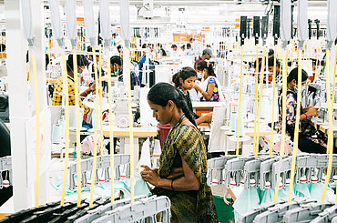 Textilarbeiterinnen und Textilarbeiter bei der Arbeit in einer Fabrik in Indien.  