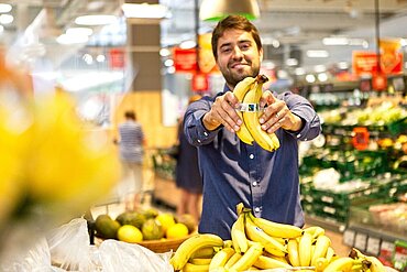 Foto eines Kunden mit Fairtrade-Bananen in einem Supermarkt.