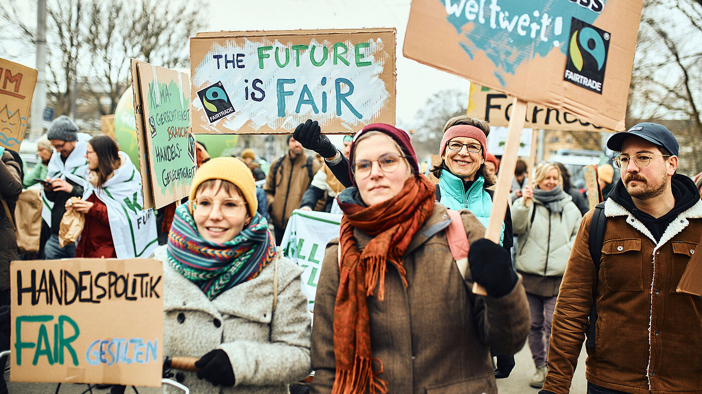 Menschen auf einer Klimademo - vorne mittig zwei Frauen mit Schildern, auf denen KlimaFairness gefordert wird
