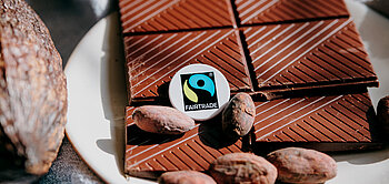  Eine Tafel Fairtrade-Schokolade und Kakaobohnen liegen auf einem Teller.