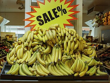 Bananen in einem Supermarkt, die mit großem "Sale"-Schild angeboten werden