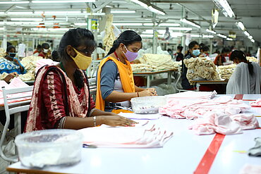 Zwei Frauen in einer Textilfabrik in Indien bei der Arbeit. 