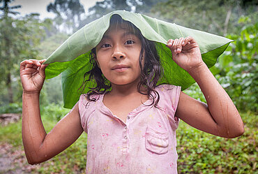 A young girl protects herself from the rain with a malanga leaf at a CORCASAN coffee farm in San Juan de Rio Coco.