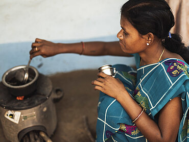 Eine indische Frau kocht mit einem modernen Kochofen.