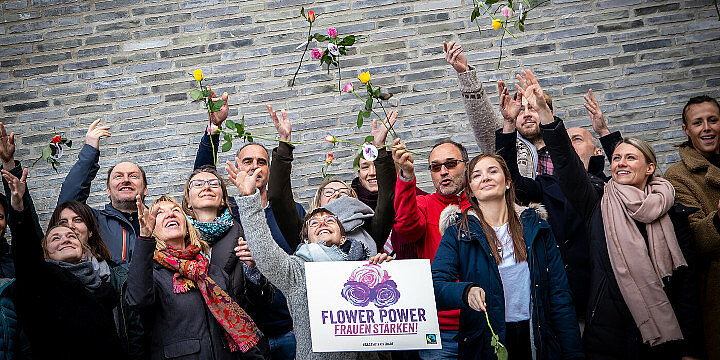 Gruppe von Menschen hält ein Plakat "Flaower Power" und wirft Rosen in die Luft